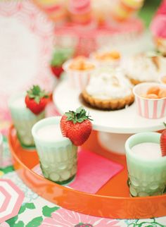 desserts and cupcakes are arranged on an orange platter with pink napkins