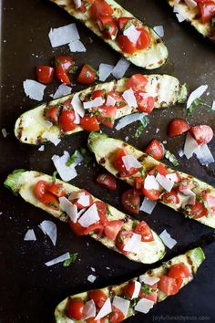 avocado and tomato stuffed zucchini boats on a baking sheet