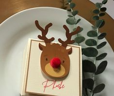 a white plate topped with a card and a reindeer head