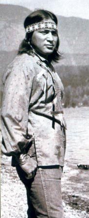 an old black and white photo of a native american man standing in front of a lake