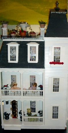 a doll house with lots of windows and decorations on the top floor is shown in front of a painting