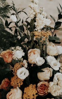 a bunch of flowers that are sitting on a table in front of some leaves and plants