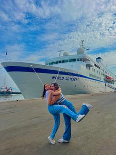 two people are dancing in front of a large cruise ship on the water with their arms around each other