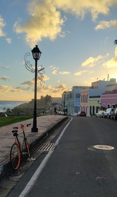 a bike parked on the side of a road next to a street light and ocean