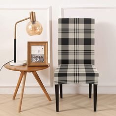 a white and black checkered chair next to a wooden table with a clock on it