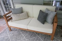 a white couch sitting on top of a rug next to a wooden frame and window