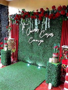 a green carpeted stage set up with red roses and greenery on the side