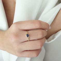 a woman's hand wearing a gold ring with an oval blue stone on it