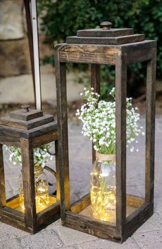 two small wooden lanterns with flowers in them