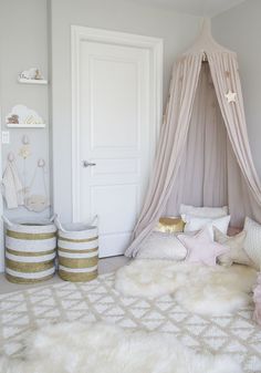 a white bedroom with a canopy bed and pillows on the floor in front of it