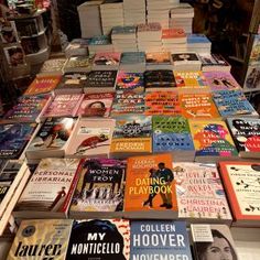 many books are stacked on top of each other in front of a table full of them