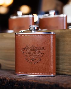 a leather flask is sitting on top of a wooden box with two lighters in it