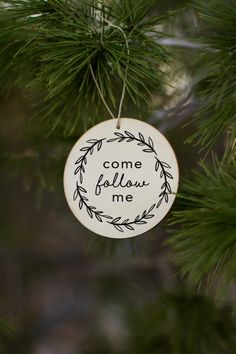 a ceramic ornament hanging from a tree with the words come follow me on it