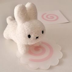 a small white stuffed animal sitting on top of a table next to a pink target