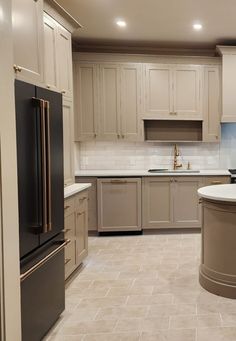 a large kitchen with white cabinets and gray counter tops, an island in the middle