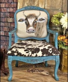 a cow painted on the back of a blue chair with flowers in front of it