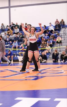 two women wrestling in a gym with spectators watching