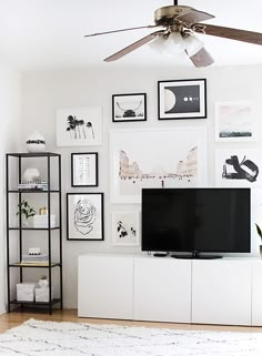 a living room with pictures on the wall and a flat screen tv sitting on top of a white entertainment center