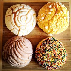 four different types of doughnuts on a wooden surface