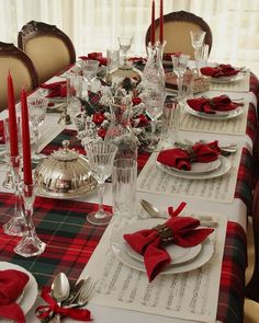 a table set for christmas dinner with red napkins and silverware on top of it