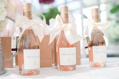 three bottles of wine are sitting on a table with flowers in vases behind them