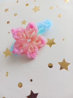 two pink and blue hair clips sitting on top of a white surface with gold stars