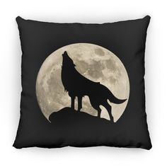 a black pillow with a wolf silhouette on it and the moon in the back ground