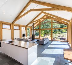 an open kitchen and living room area with wood beams on the ceiling, large windows in the background