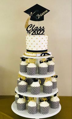 a tiered cake with cupcakes on it and a graduation cap on top