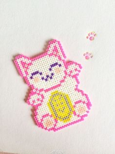 a cross - stitch hello kitty brooch sits on top of a piece of paper