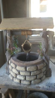 an outdoor fountain made out of rocks and logs