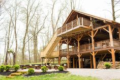 a large wooden house in the woods with stairs leading up to it's second story