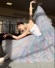 a woman in a white and blue dress is dancing on the floor with her legs spread out