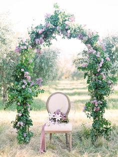 a chair sitting under an arch covered in flowers