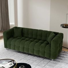 a green couch sitting on top of a living room floor next to a table and lamp