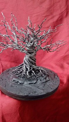 a metal tree sculpture sitting on top of a red cloth