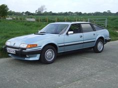 a blue car is parked on the side of the road in front of some green grass