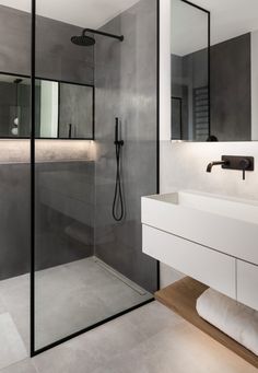 a bathroom with a glass shower door, sink and mirror on the wall next to it