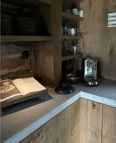 an open book sitting on top of a counter next to a blender and coffee maker