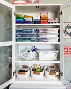 an organized closet with craft supplies and quilts on shelves in front of glass doors