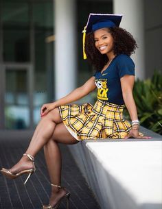 a woman sitting on top of a white wall wearing a graduation cap and yellow plaid skirt