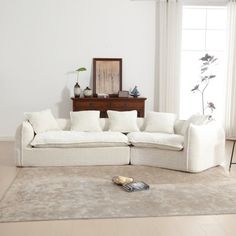 a white couch sitting on top of a rug in a living room next to a window