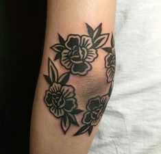 a woman's arm with black and white flower tattoos on her left arm,