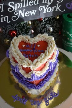 a heart shaped cake sitting on top of a table next to a sign that says i spelled my name in new york