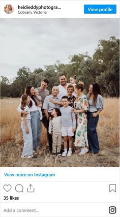 the family is posing for a photo together in an open field with trees behind them