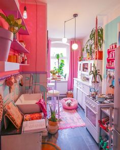 a kitchen with pink walls and lots of potted plants