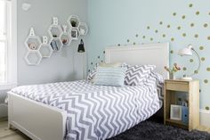 a bed room with a neatly made bed and polka dot wallpaper