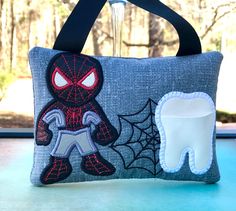 a toothbrush holder with a spiderman design on it and a tooth in the background