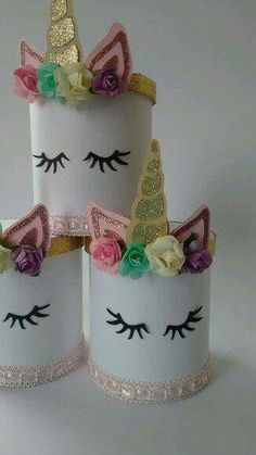 three white cups with unicorn faces and flowers on them, one has a pink ribbon around the top