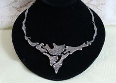 This is a handsome 1970s mid-century necklace by Quebec Brutalist studio artist, Jean Claude Darveau.  The necklace has an abstract, textured organic design.  The center front section of the necklace is a triangular shape, with organic forms with negative spaces.  The necklace links have similar organic shapes.  The necklace is silver plated pewter, with a bright silver tone finish.   The necklace is well made, and is in excellent condition.  The jump rings between the large 1.75-inch links are soldered closed.  The closure is a rectangular, patented clasp which closes opens and closes with pressure. The necklace is stamped DARVEAU, plus a logo of a circle in a square. DIMENSIONS Total length of the necklace, fully extended: 17.5 inches  Width and height of the triangular front section: 5 Brutalist Jewelry, Studio Artist, Organic Forms, Organic Design, Organic Form, Wedding Jewellery Necklace, Organic Shapes, Wedding Necklace, Jump Rings